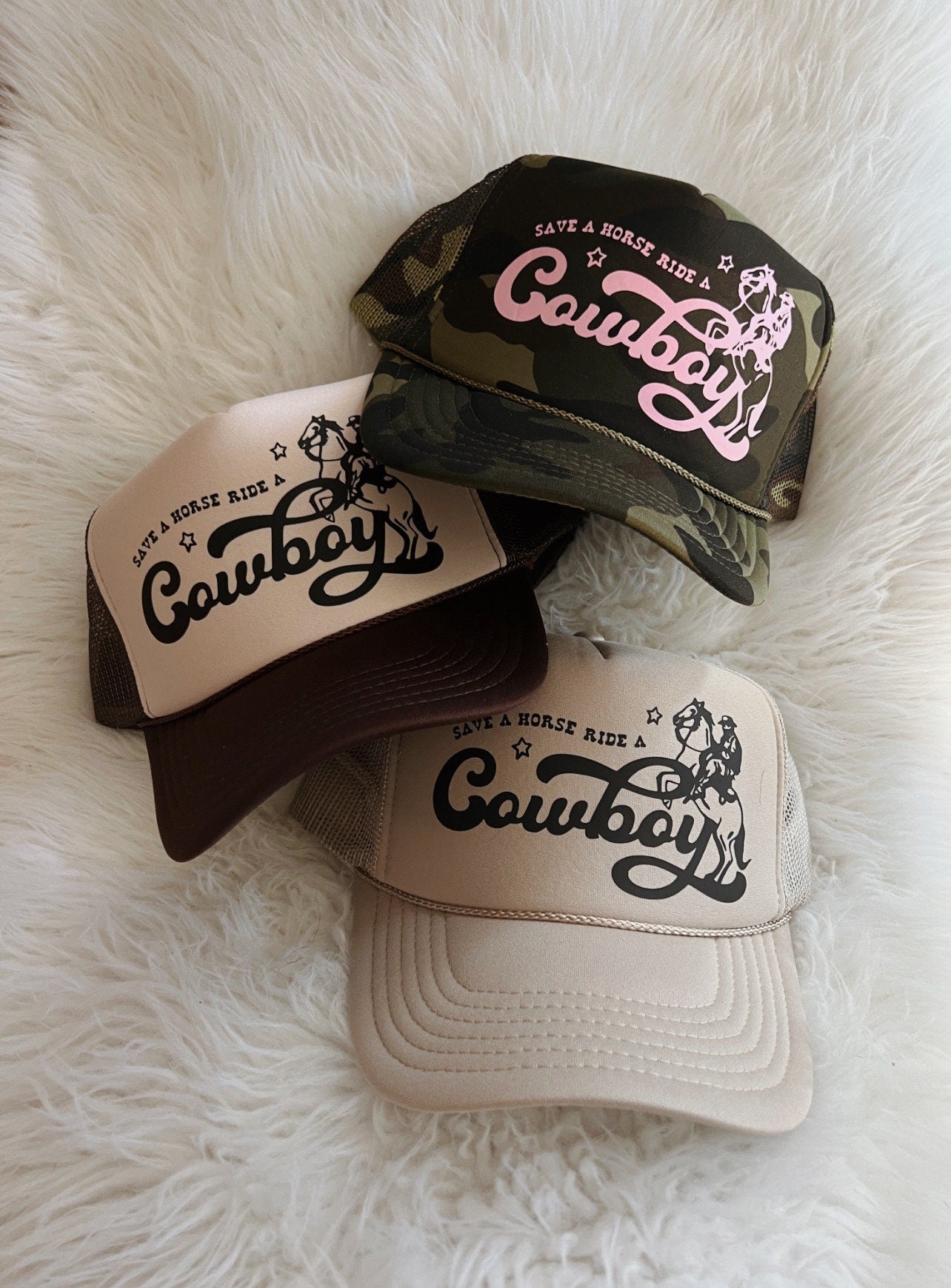 Hats shown in image: Top: All Over Camo hat (currently out of stock), Light Pink design Middle: Brown/Tan hat, Black design Bottom: Khaki hat, Black design